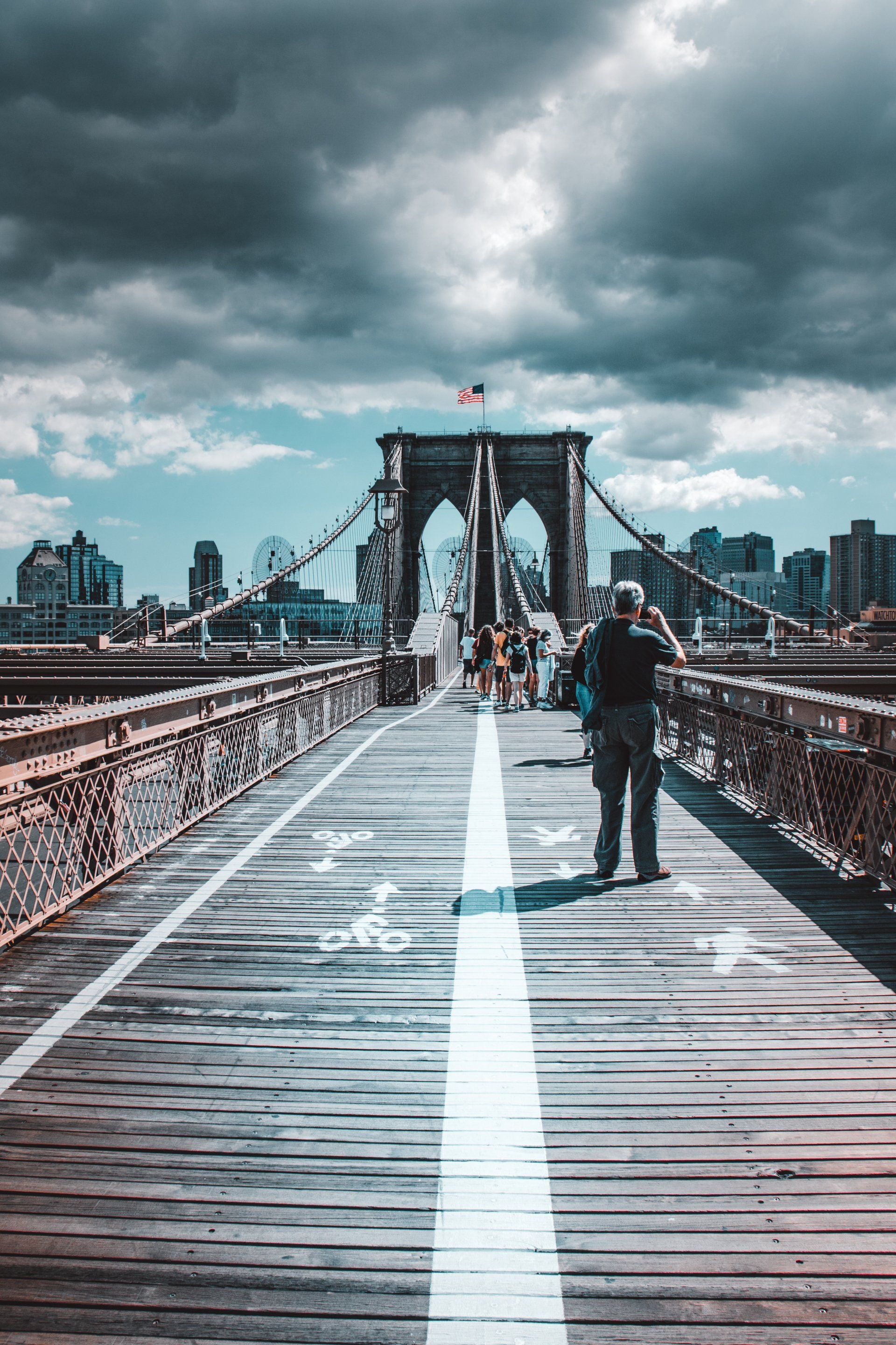 A man is walking across the Brooklyn
 bridge in new york city.