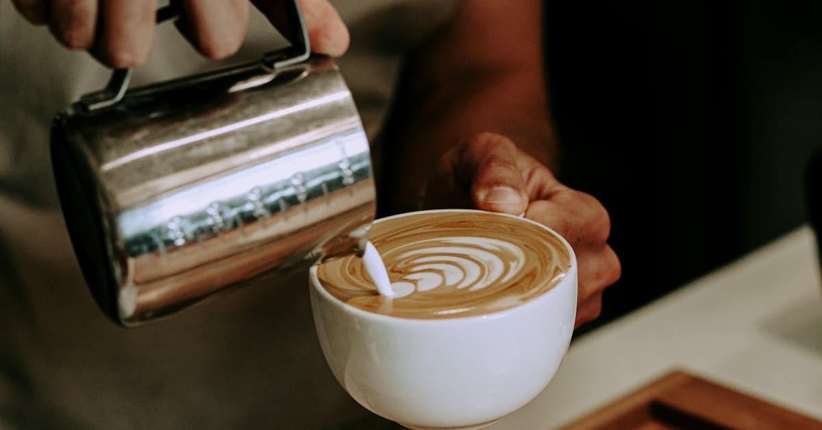 A person is pouring milk into a cup of coffee.