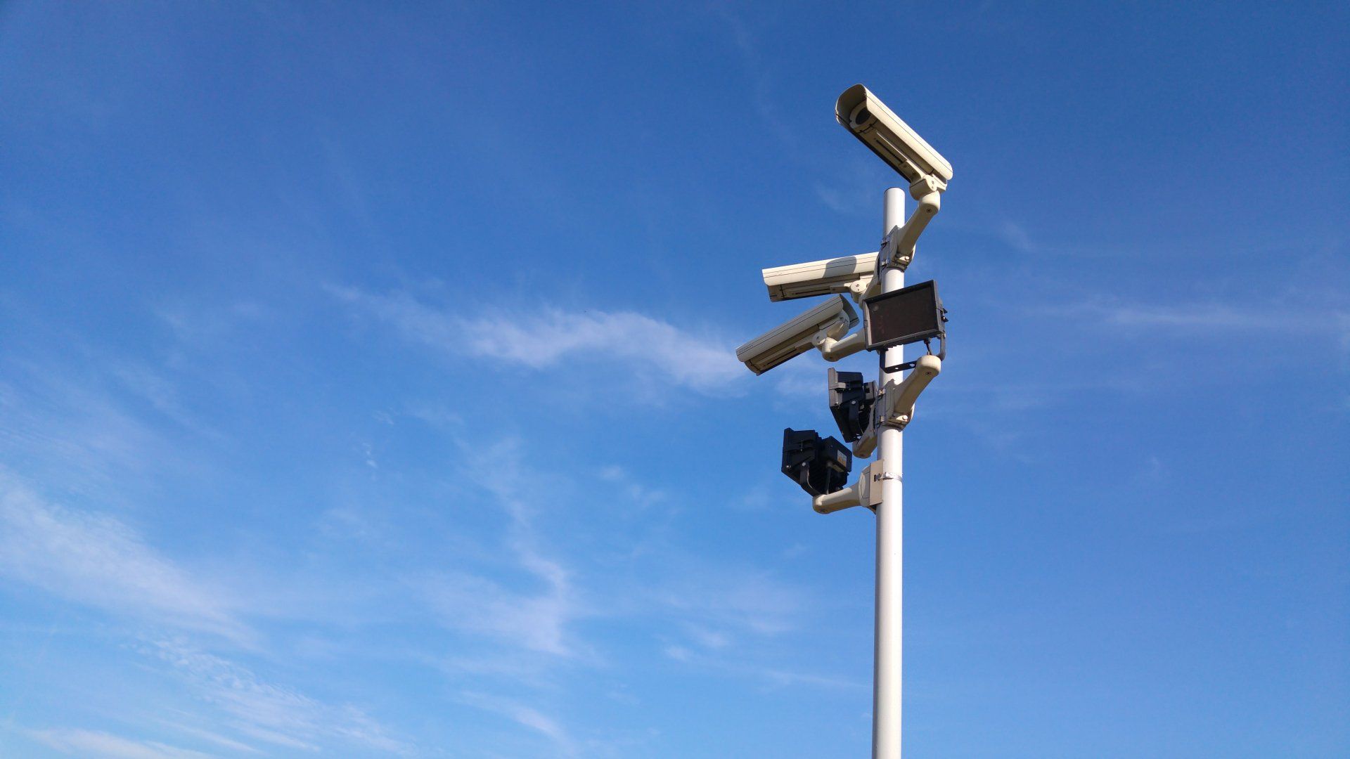 a row of security cameras on a pole against a blue sky .