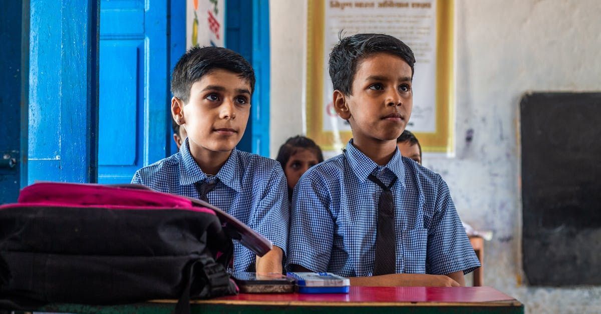 Two young boys are sitting at their desks in a classroom.