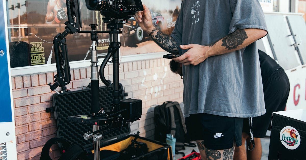 A man is standing in front of a camera on a tripod.