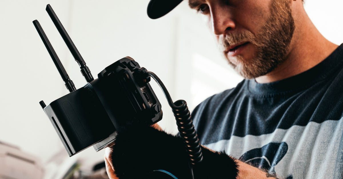 A man is holding a camera with two antennas attached to it.