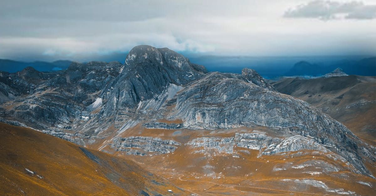 An aerial view of a mountain range with a cloudy sky in the background.