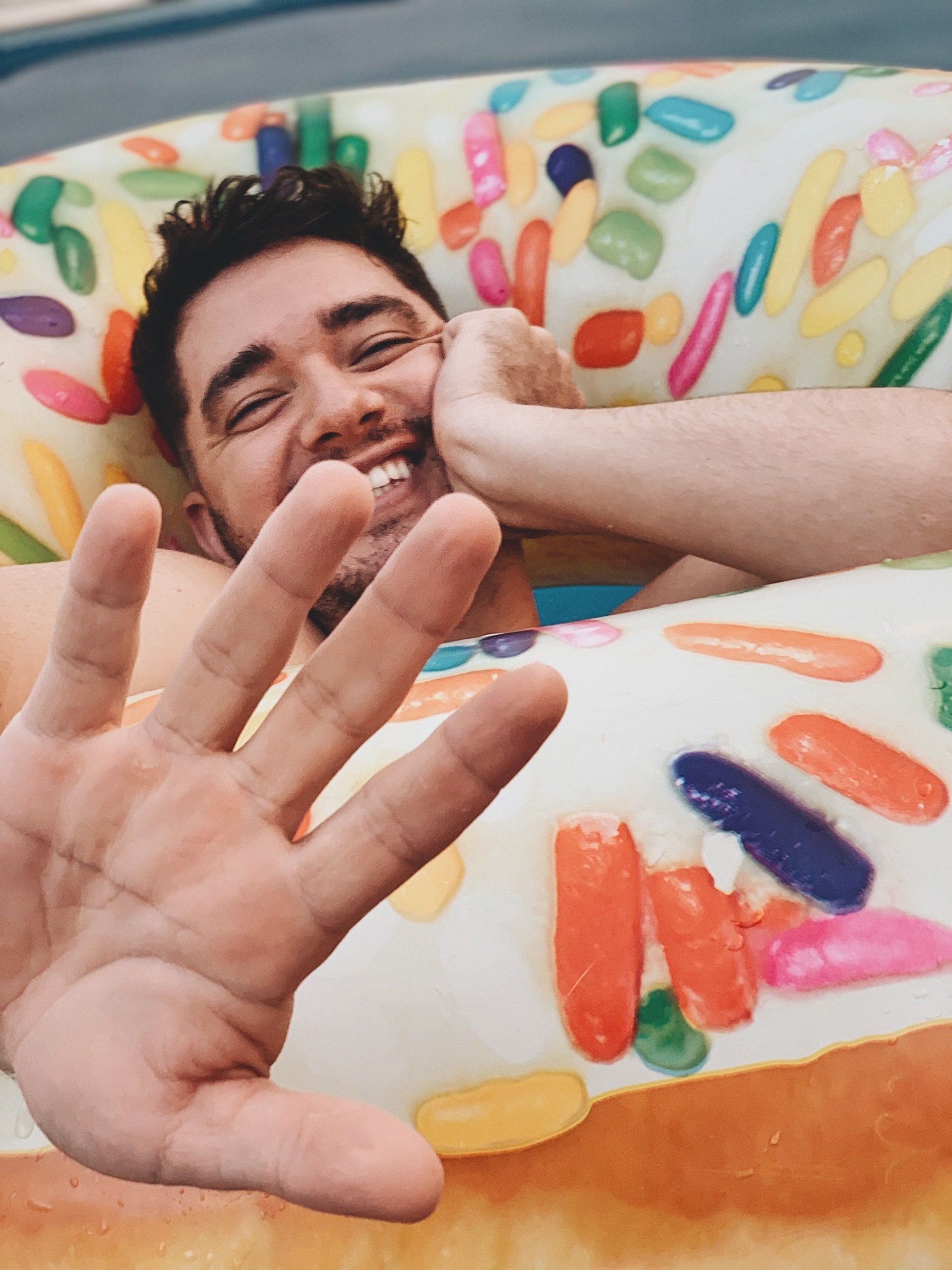A man is laying on a donut shaped blanket with sprinkles on it