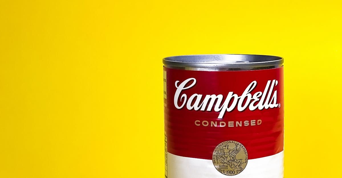 A can of campbell 's soup is on a yellow background.