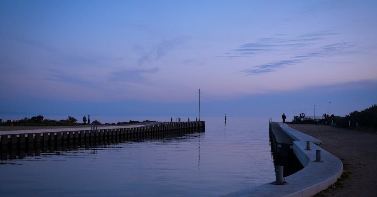 A group of people are standing on a pier overlooking a body of water.