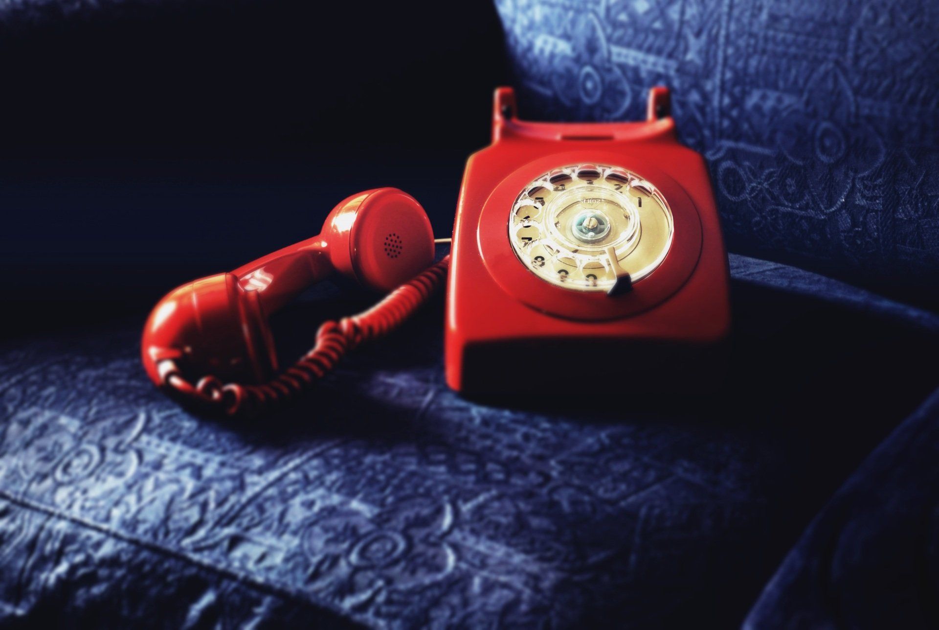 A red telephone is sitting on a blue couch