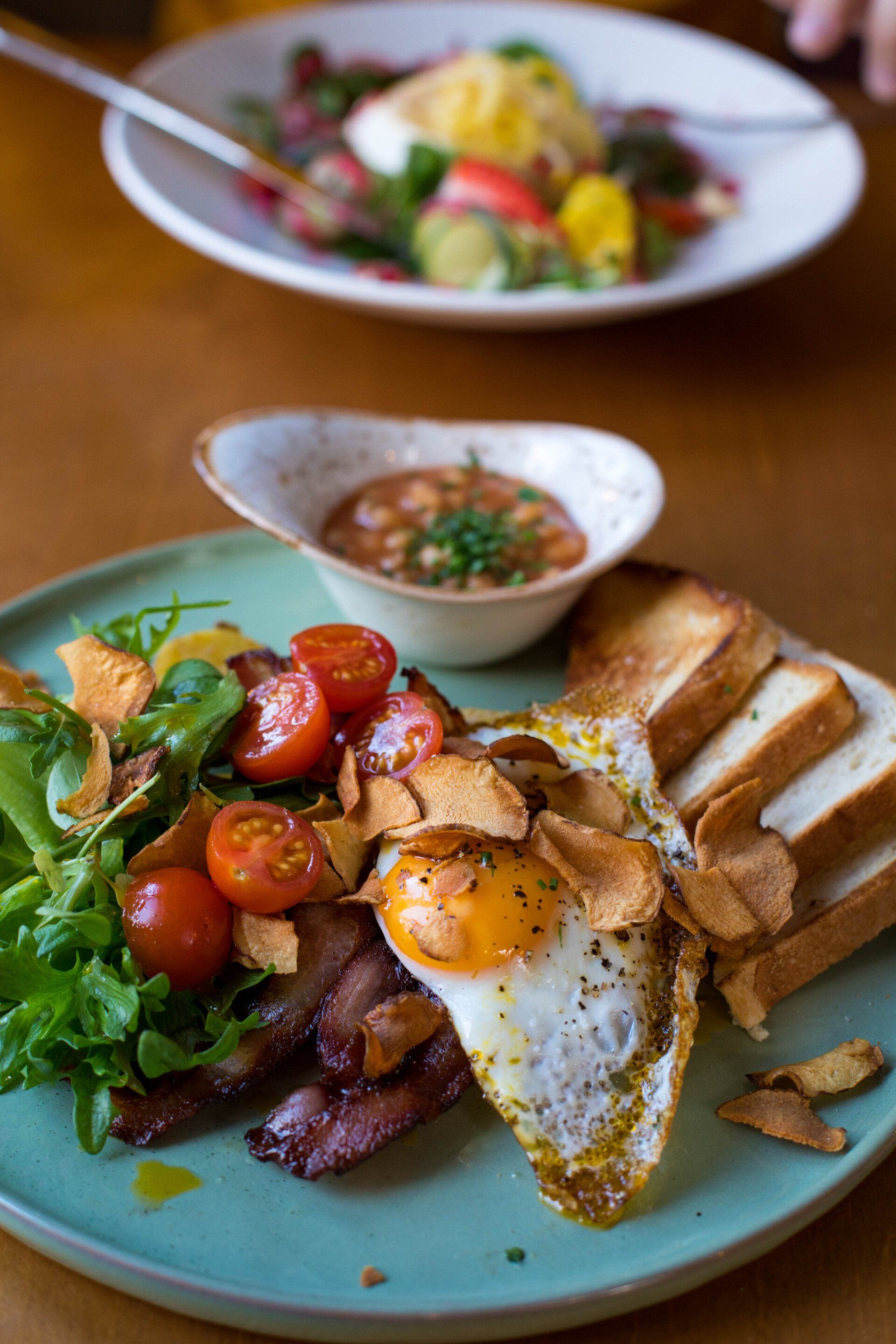A plate of food with eggs , bacon , tomatoes and toast on a table.