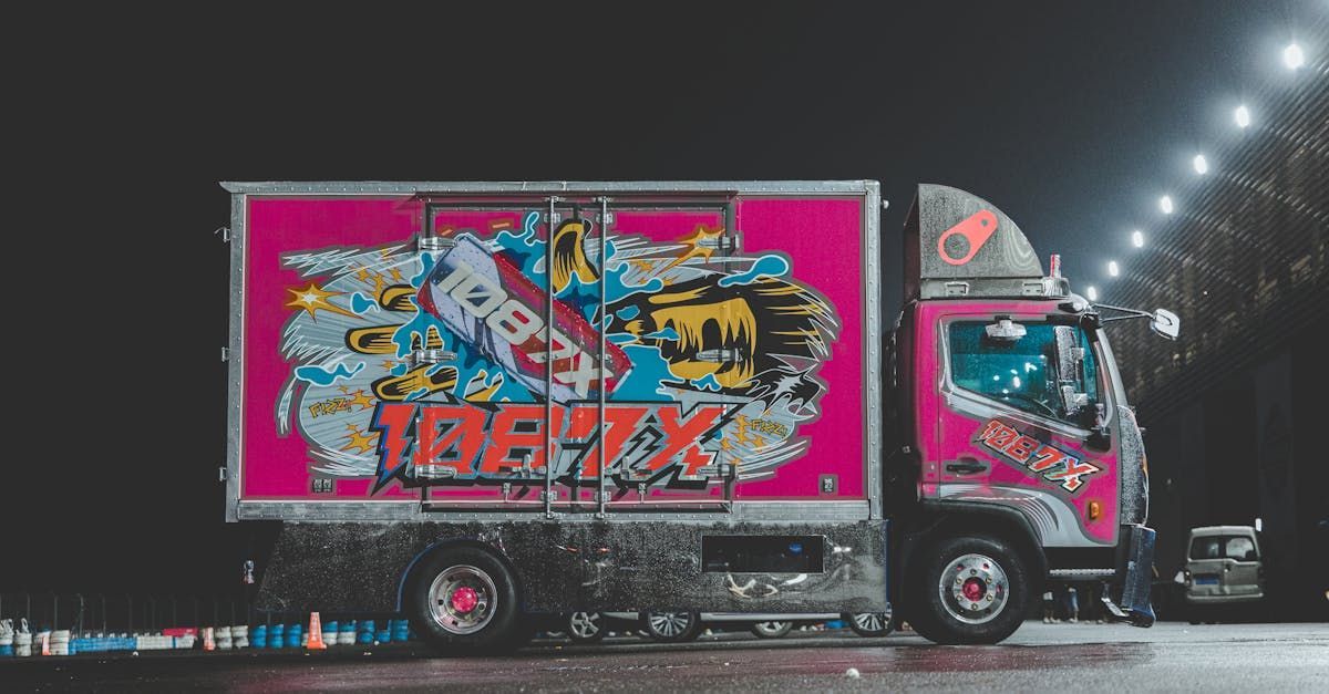 Pink and chrome truck with elaborate graffiti art, parked at night.