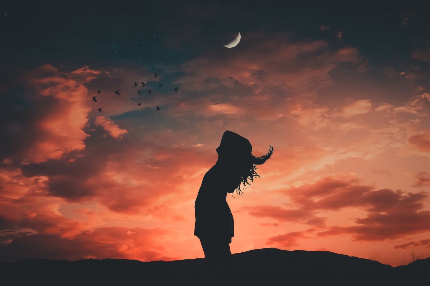 A woman stands in front of a sunset with a crescent moon in the sky