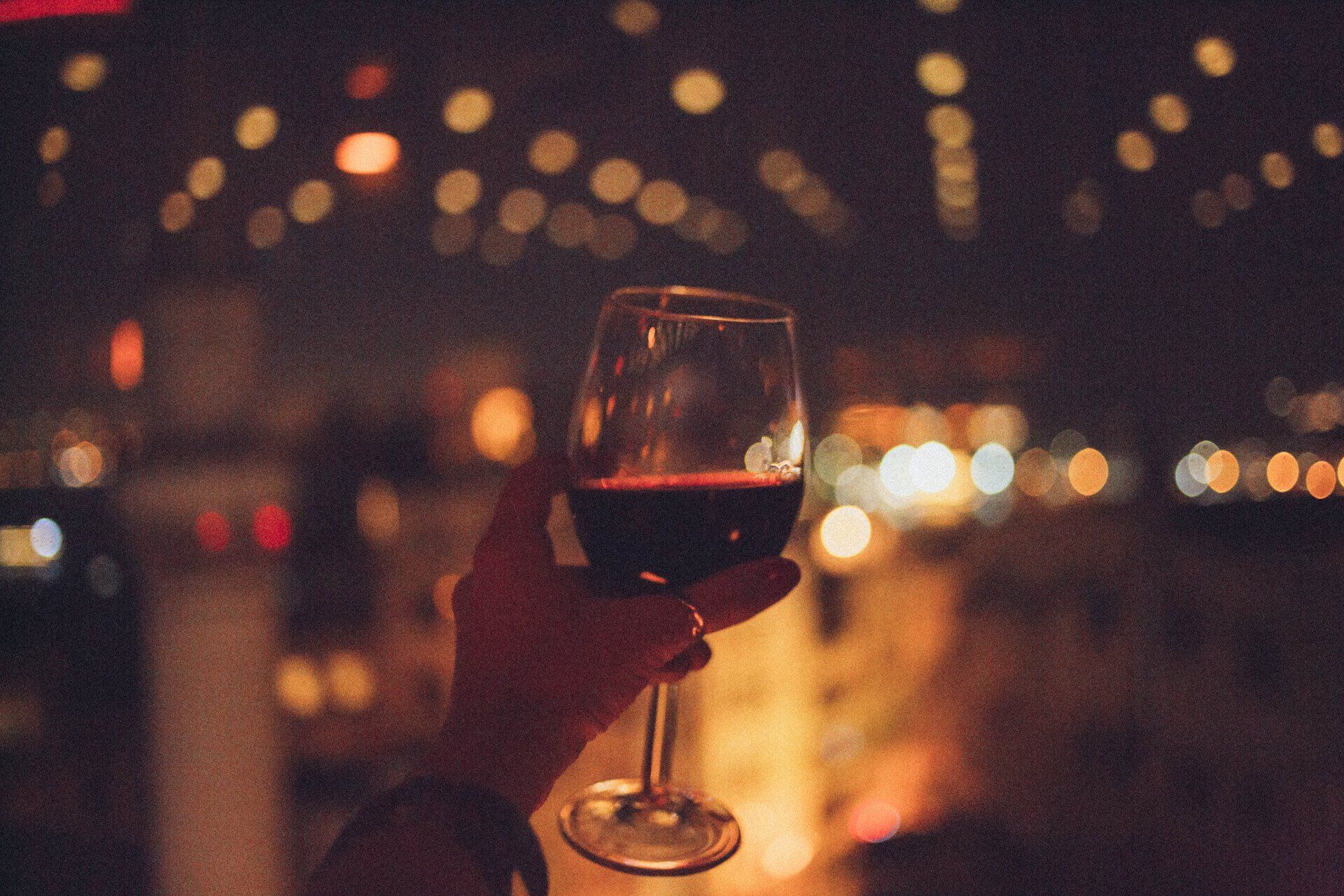 A person is holding a glass of red wine in their hand.