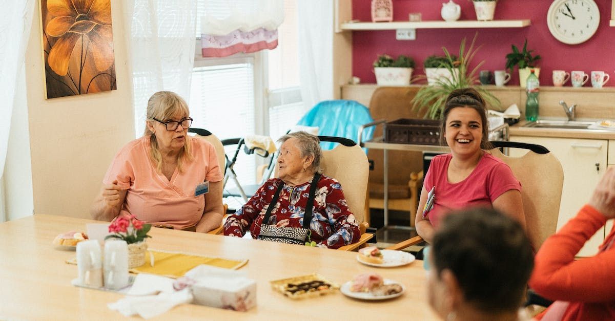 A group of elderly women are sitting at a table in a nursing home.