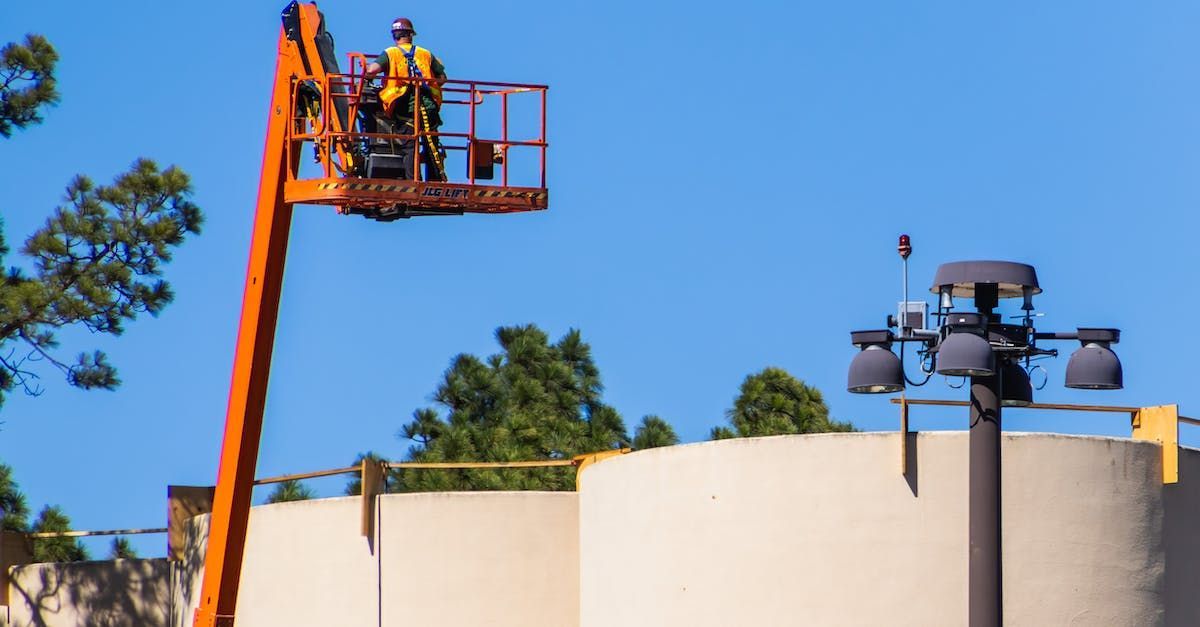 A man is standing on a crane over a building.