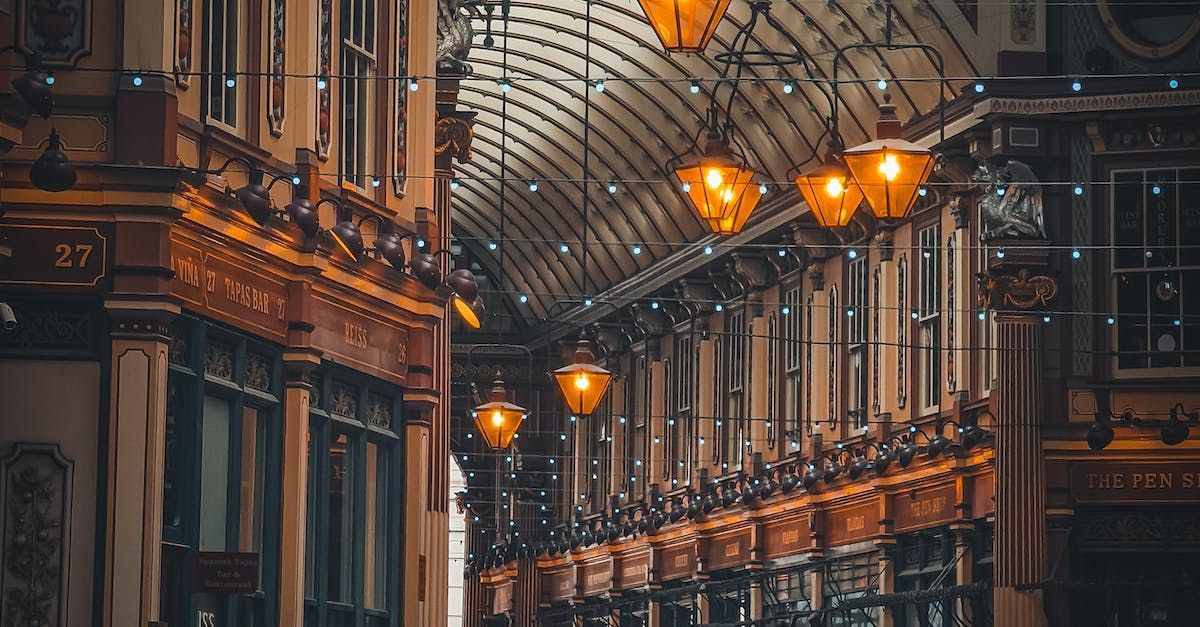 An interior view of a long, arched shopping arcade at night, with warm lighting and ornate architectural details.