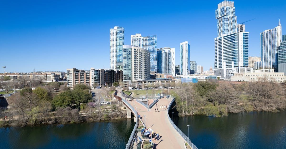 An aerial view of a bridge over a body of water with a city skyline in the background.