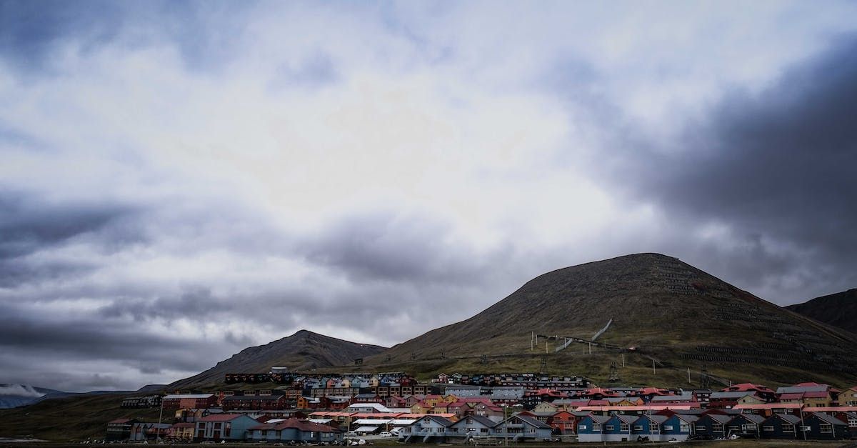 A small town is surrounded by mountains and clouds on a cloudy day.