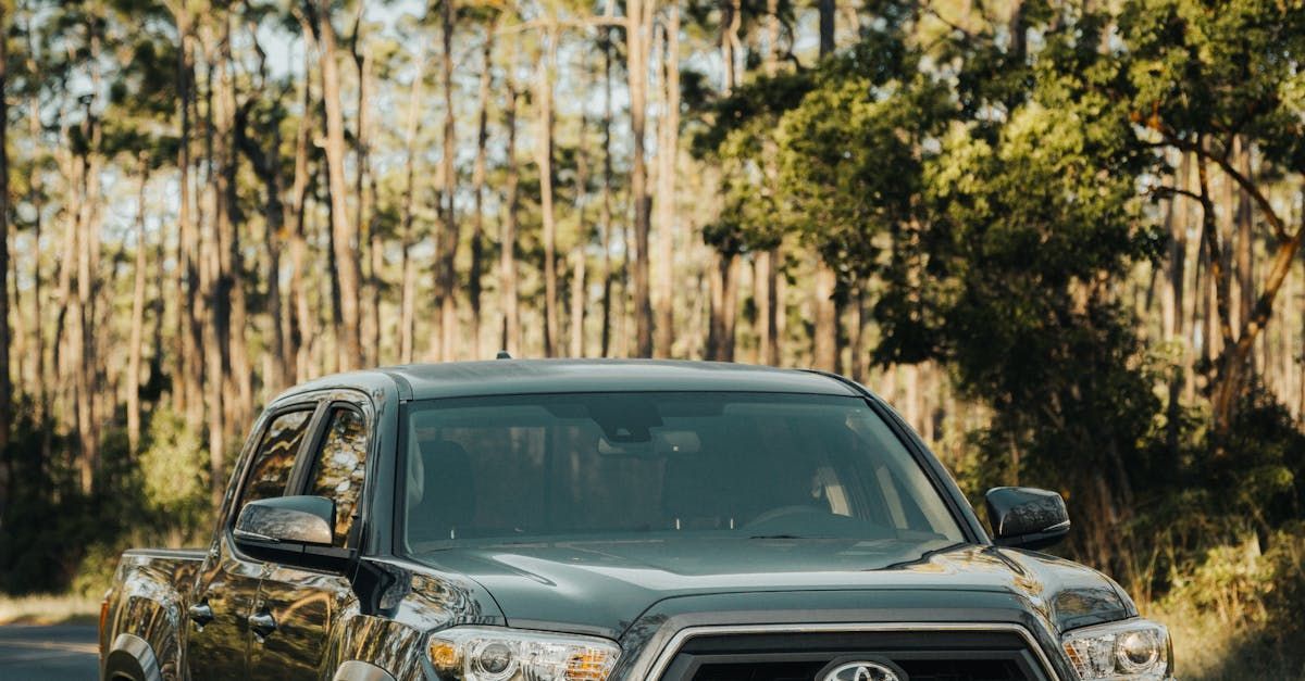 A toyota tacoma truck is driving down a road in the woods.