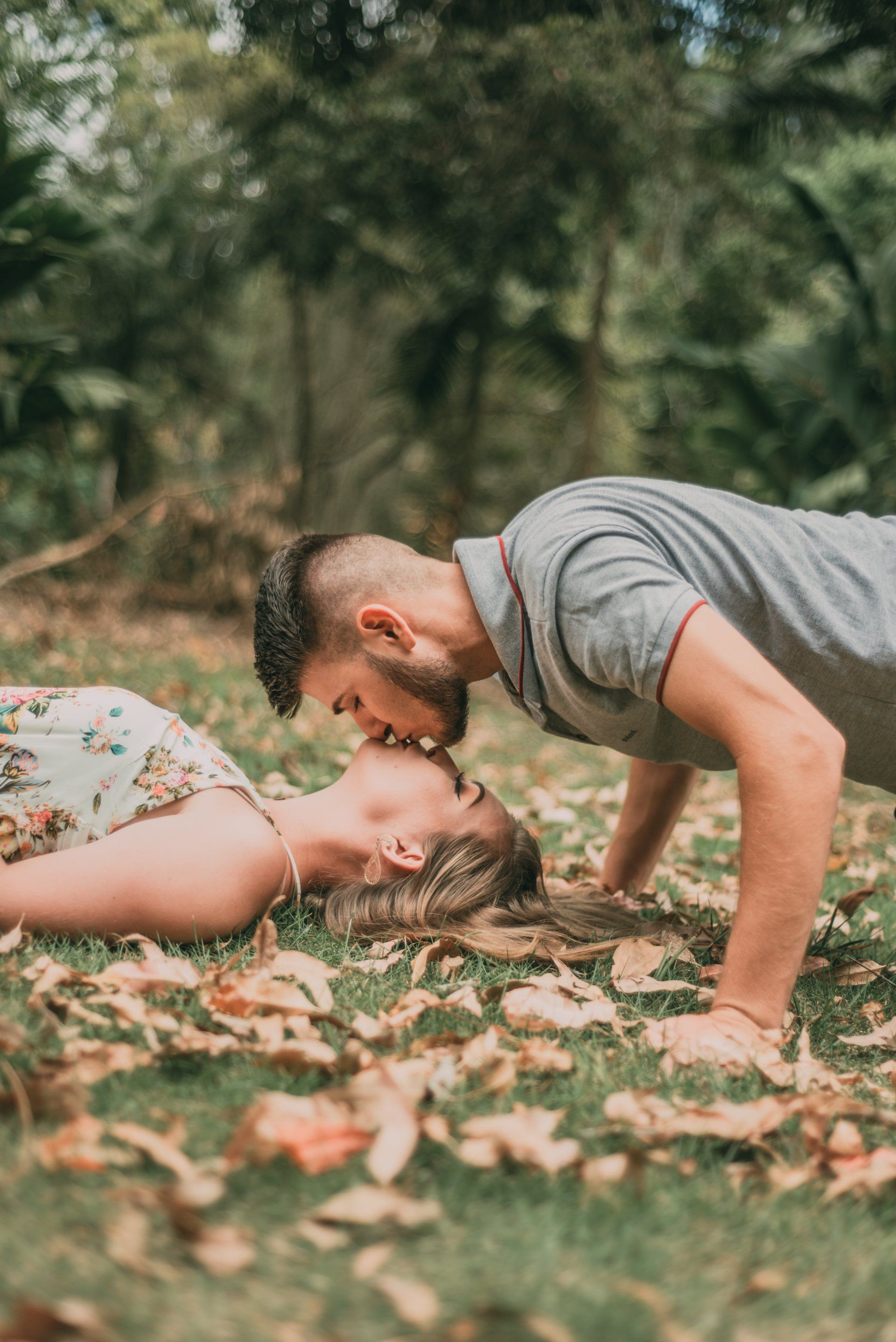 a man and a woman are kissing in the grass