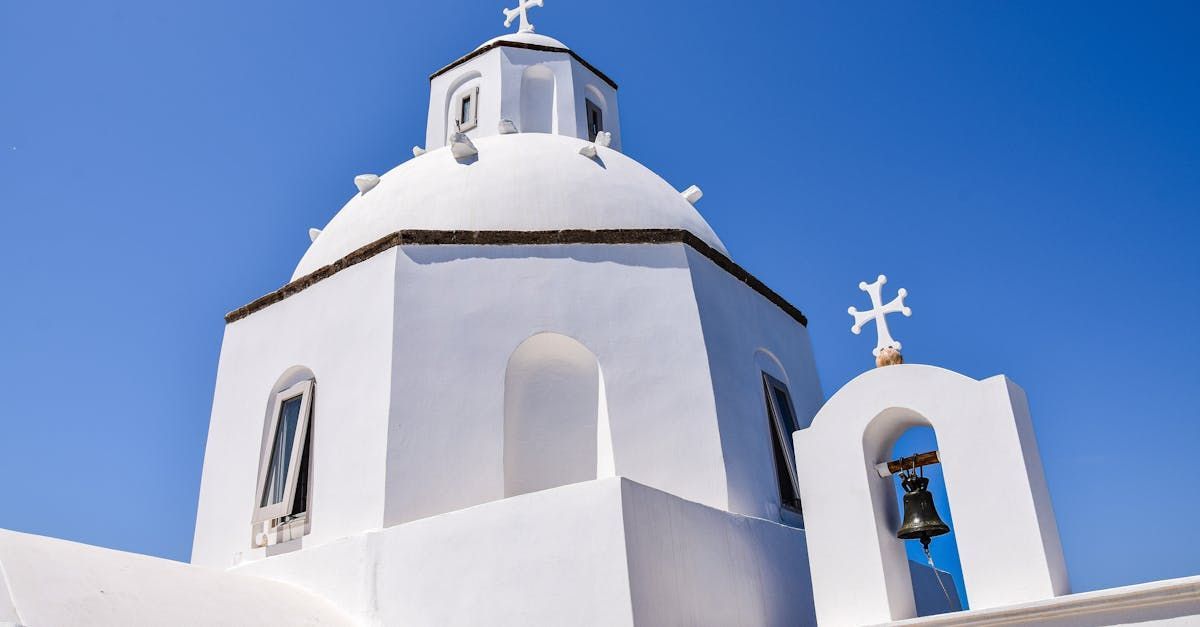 A white church with a dome and a bell tower against a blue sky.