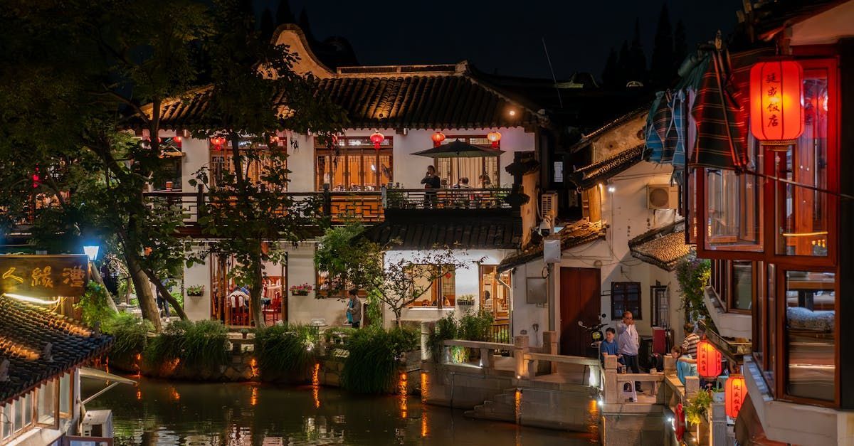 A group of people are standing in front of a building next to a river at night.