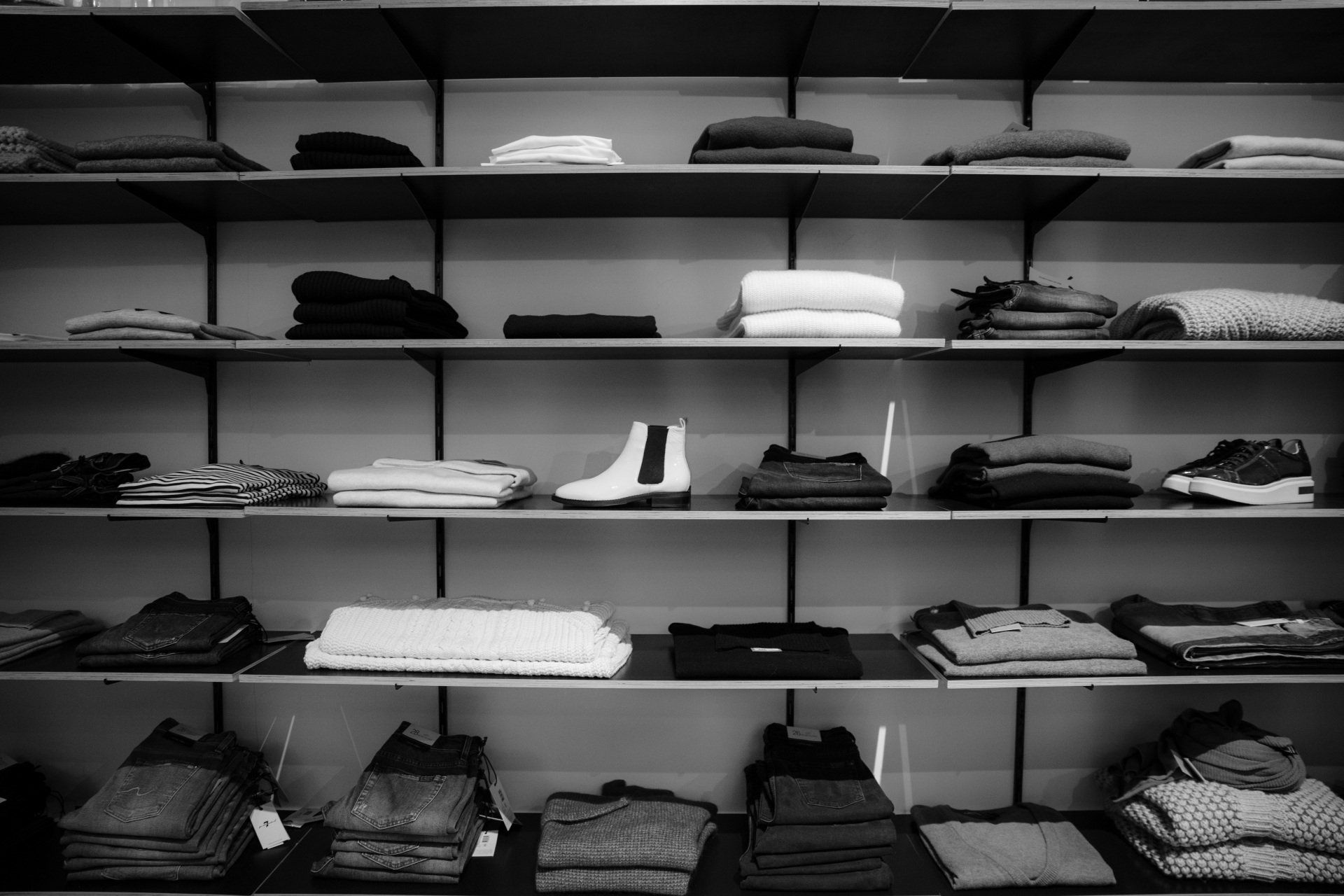 a black and white photo of a closet filled with clothes and shoes.