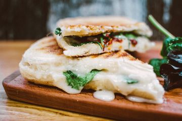 A close up of a sandwich on a wooden cutting board.