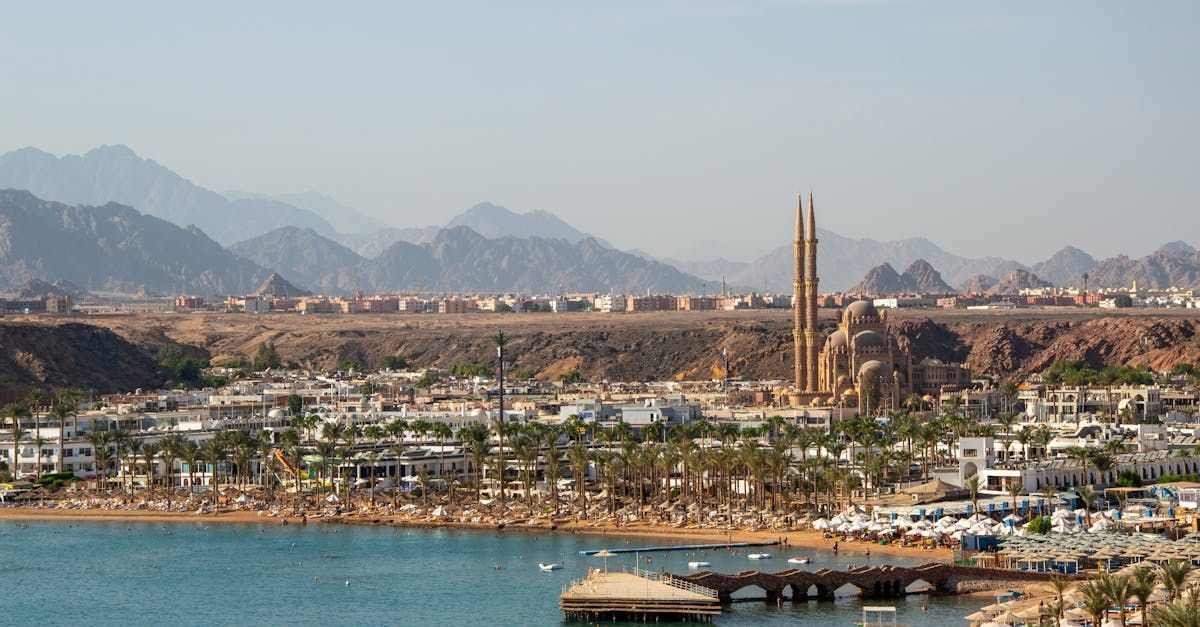 An aerial view of a city with mountains in the background and a body of water in the foreground.