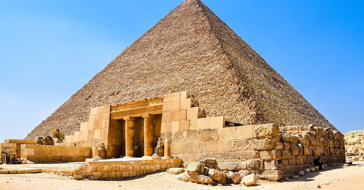 A large pyramid in the middle of the desert with a blue sky in the background.