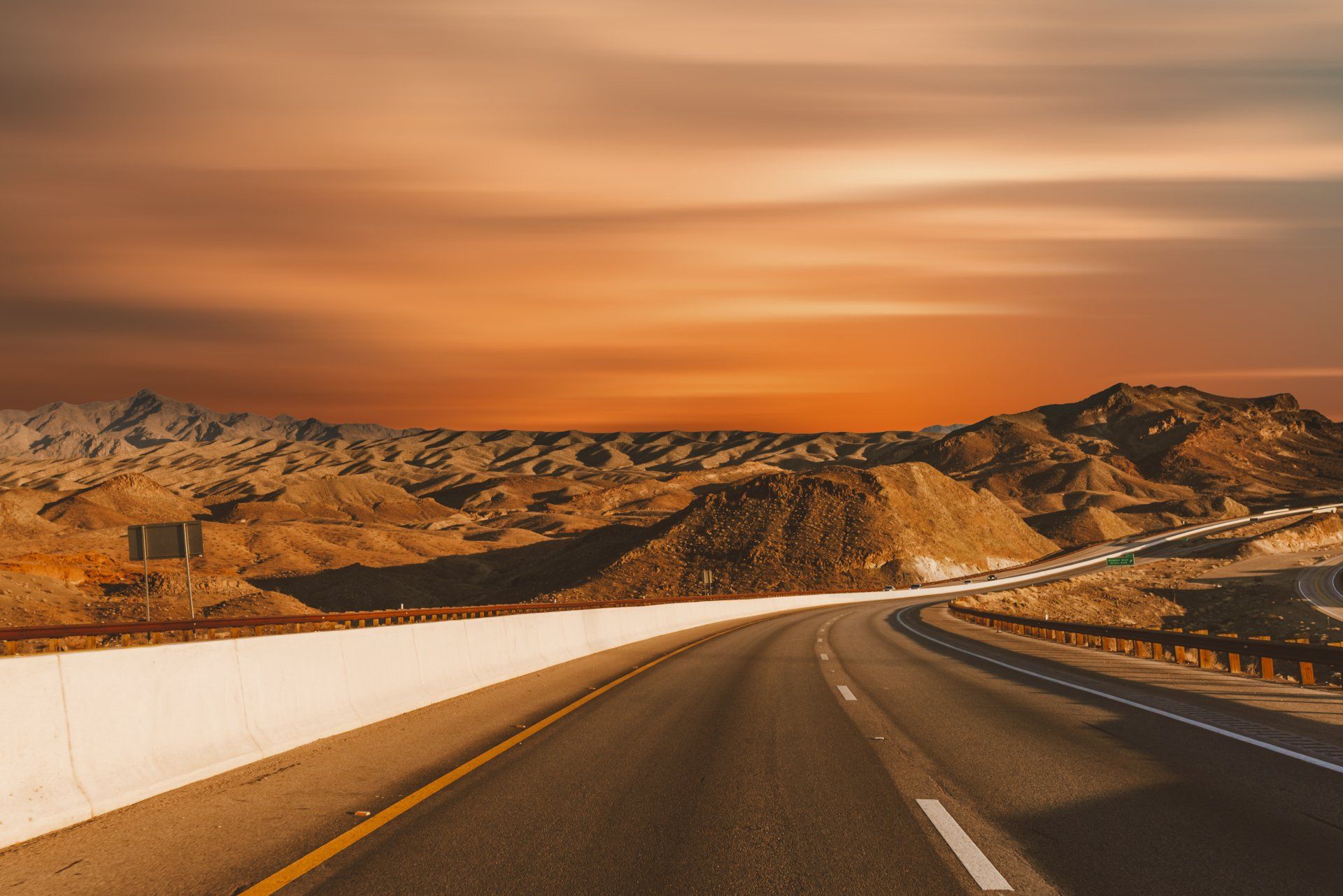 a road going through a desert with mountains in the background at sunset