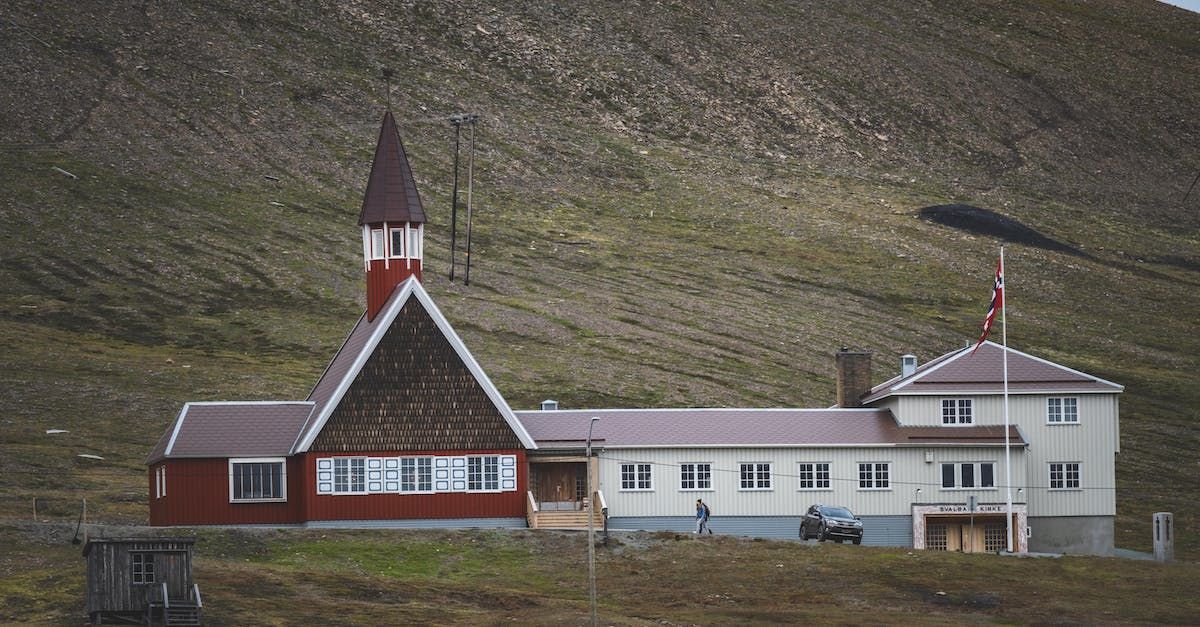 A large red and white building with a steeple is sitting on top of a hill.