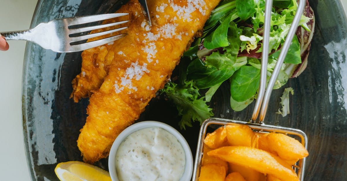 Eine Person hält eine Gabel über einen Teller mit Fish and Chips.