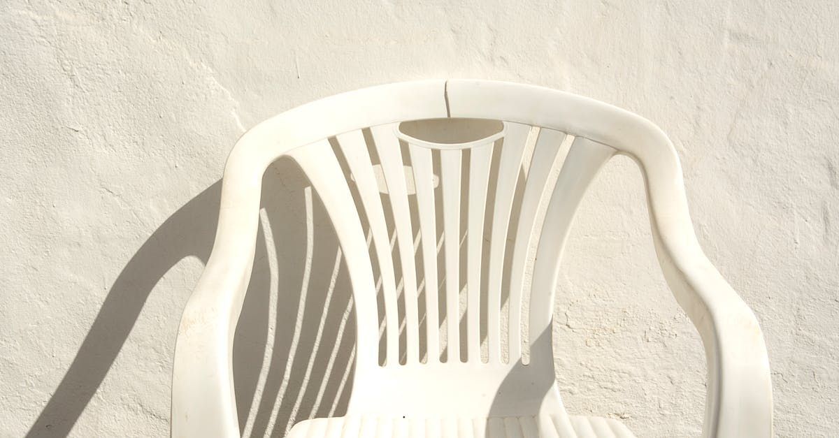 A white plastic chair is sitting in front of a white wall.