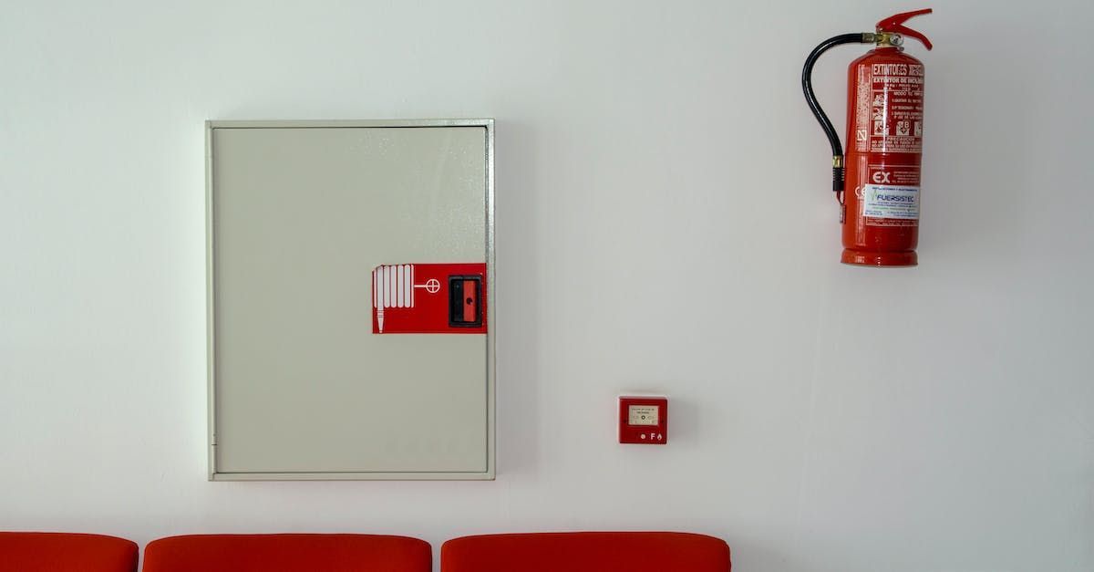 a red fire extinguisher is hanging on a white wall