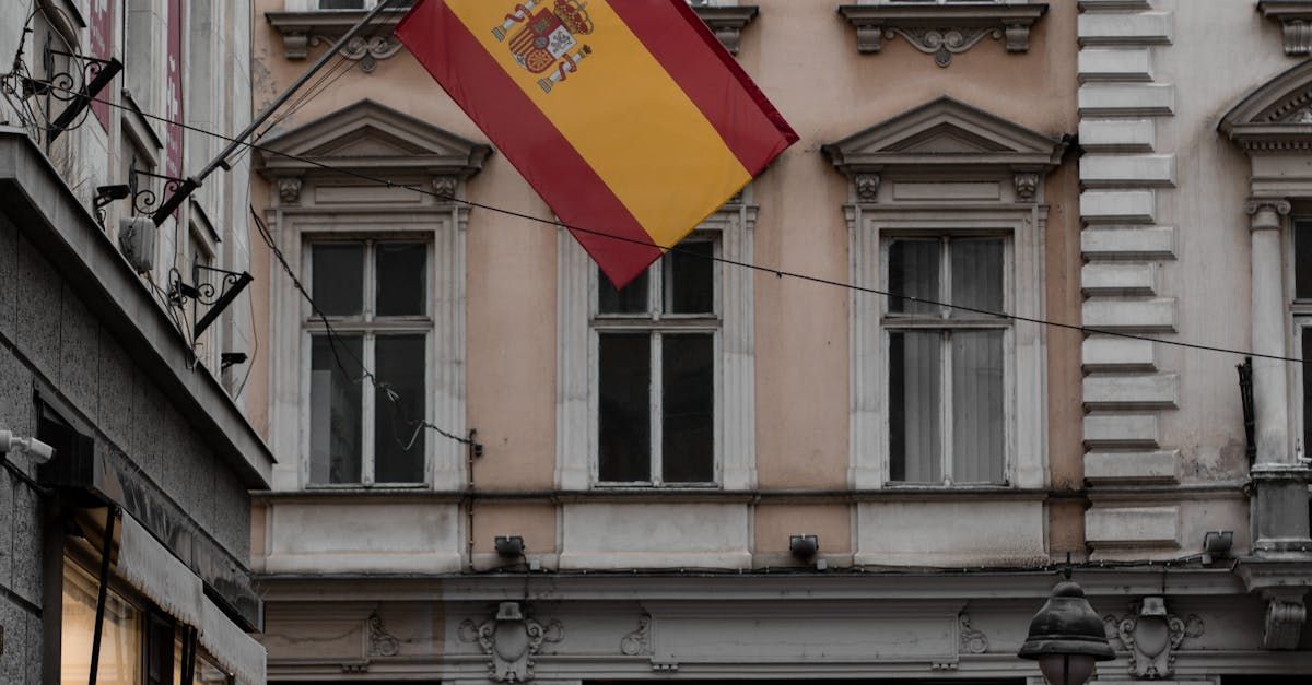 Una bandera española ondea frente a un edificio.