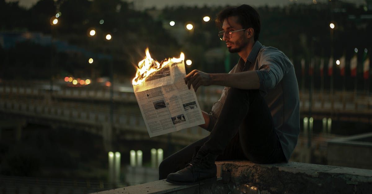 A person holding a burning newspape