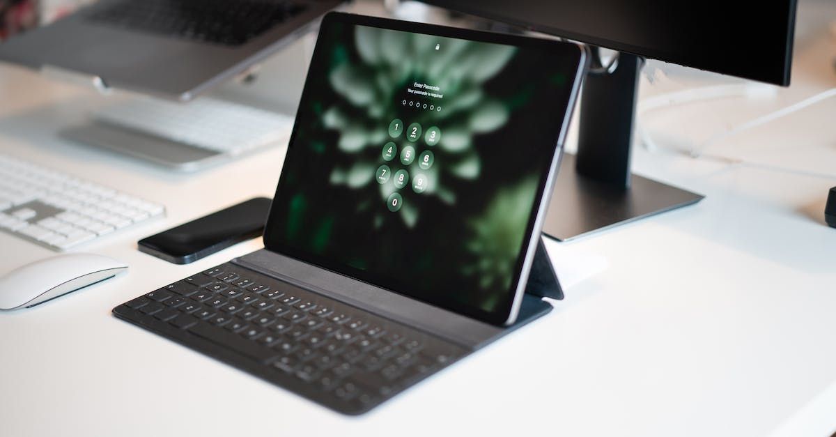 A tablet is sitting on top of a keyboard on a desk.