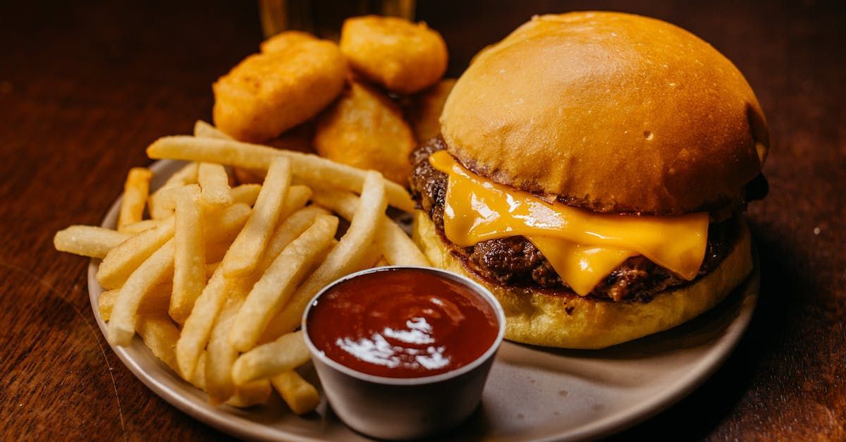 A hamburger and french fries on a plate with ketchup.