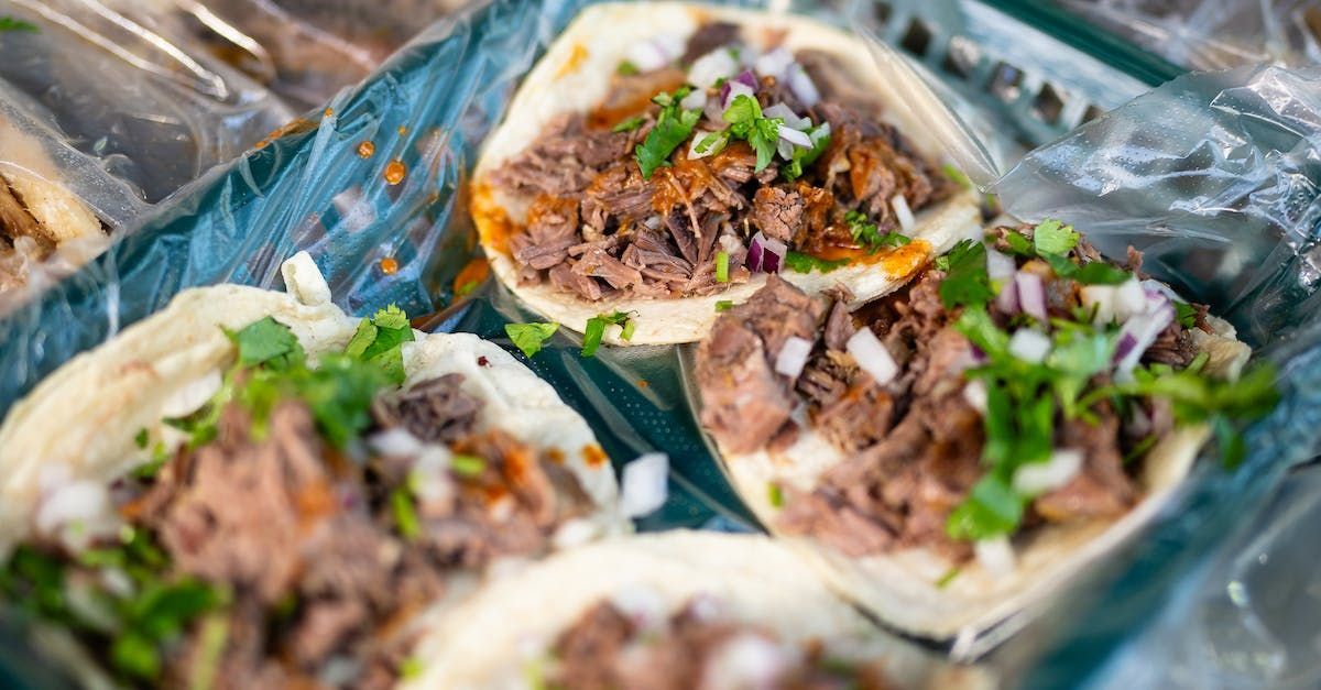 A close up of a plate of tacos with meat and vegetables on a table.