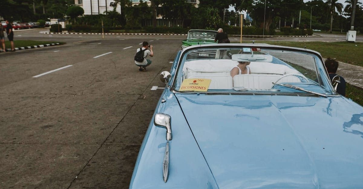 A man is taking a picture of a blue car