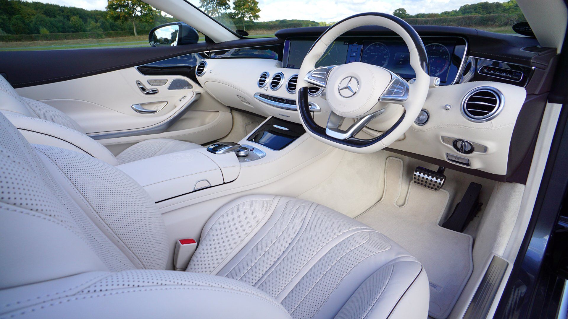 The interior of a mercedes benz car with white leather seats and a steering wheel.