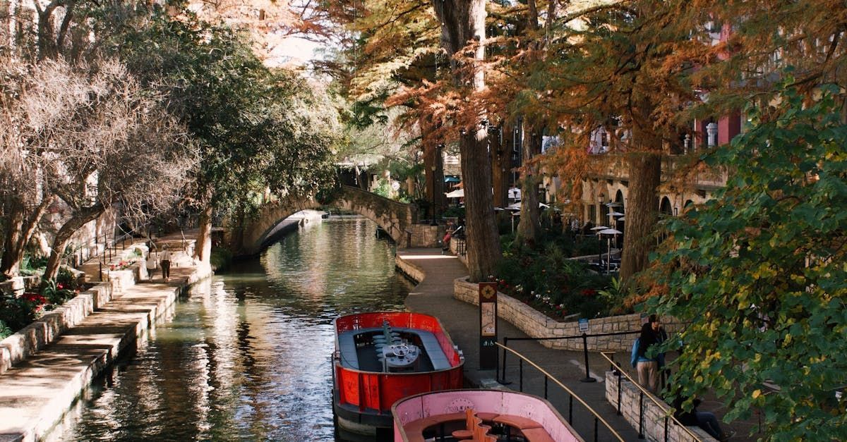 A red boat is floating down a river surrounded by trees.