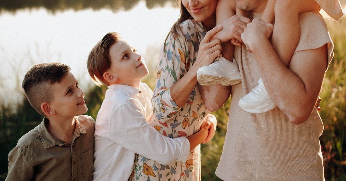 A family is standing next to each other in front of a lake.