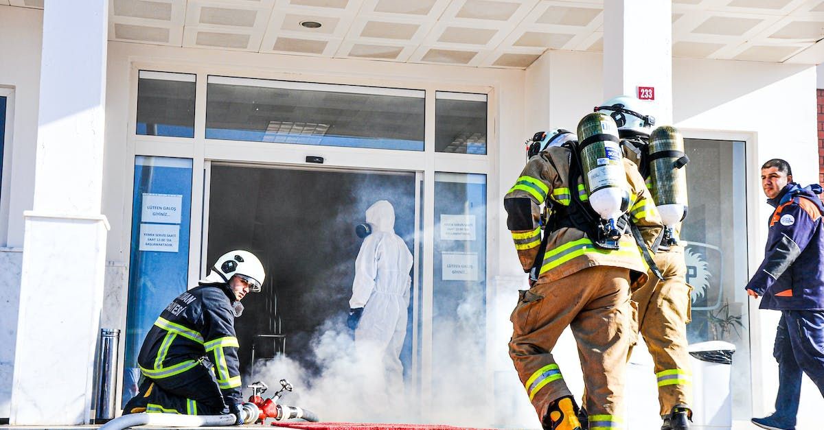 A group of firefighters are standing outside of a building.