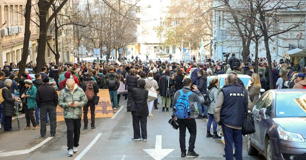 A large group of people are walking down a street.