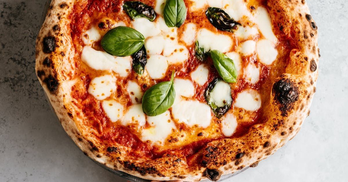 A pizza with tomato sauce , cheese and basil on a table.