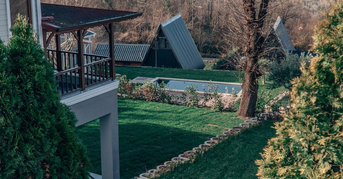A house with a porch and a swimming pool in the backyard surrounded by trees.