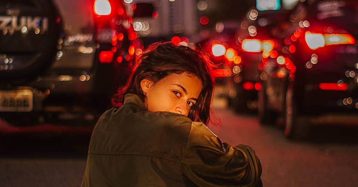 A woman is sitting on the side of the road in front of a traffic jam.