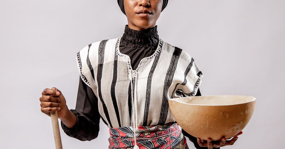 A woman is holding a wooden bowl and a wooden stick.