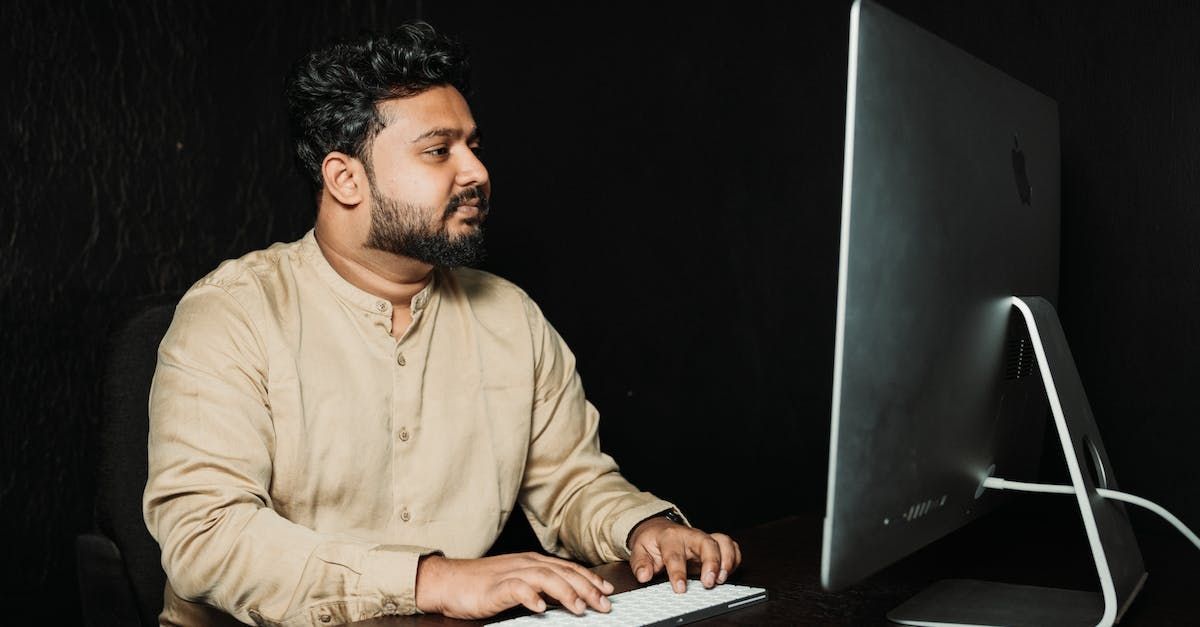 un uomo con la barba è seduto a una scrivania davanti a un computer .