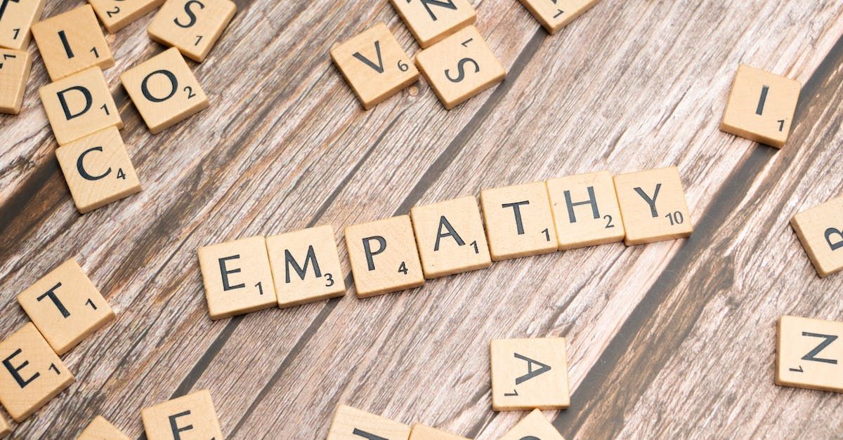 The word empathy is written in scrabble tiles on a wooden table